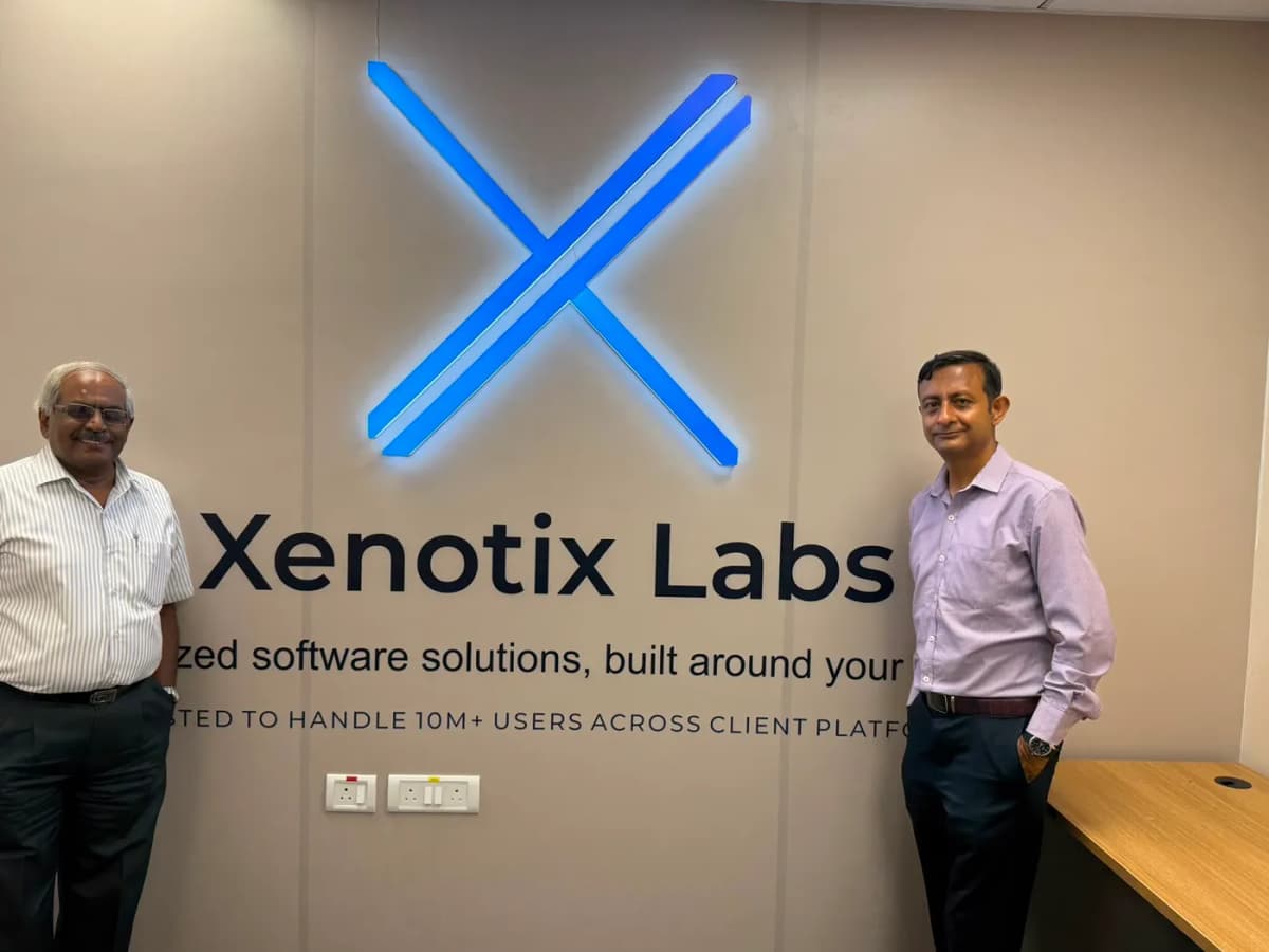 Team standing beside the Xenotix Labs logo wall